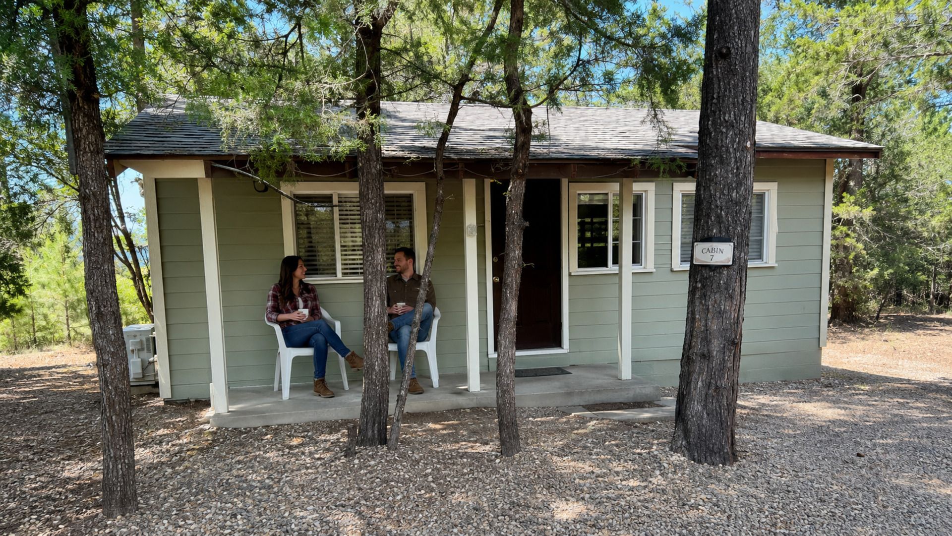 A small cabin with a porch, two chairs, and a sign indicating it is cabin number 7.