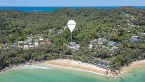 An aerial view of a coastal area with a prominent white marker labeled 'The Cove Noosa.'