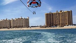 Une activité de parachute ascensionnel au-dessus d’une plage, avec des immeubles de grande hauteur en arrière-plan.
