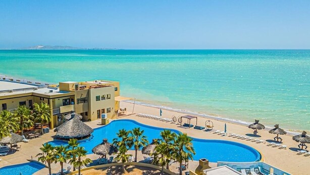 Un complexe hôtelier doté d’une piscine, d’une plage et offrant une vue sur l’océan.