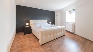 A modern bedroom with a large bed, a dark accent wall, and a skylight. - Alaska Beach with terrace by Interhome (Bredene)