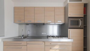 A modern kitchen with light wood cabinets, a stainless steel stove, and a built-in microwave. - Alaska Beach with terrace by Interhome (Bredene)