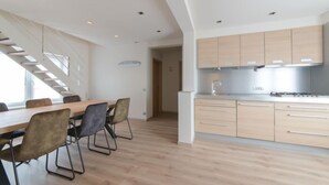 A modern kitchen with light wood cabinets, a stainless steel range hood, and a dining area with a wooden table and chairs. - Alaska Beach with terrace by Interhome (Bredene)