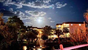 A night scene with a building, a fountain, and a clear sky.