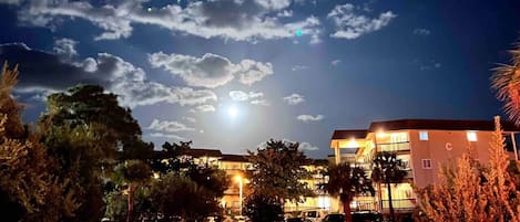 Une scène nocturne avec un bâtiment, une fontaine et un ciel dégagé.