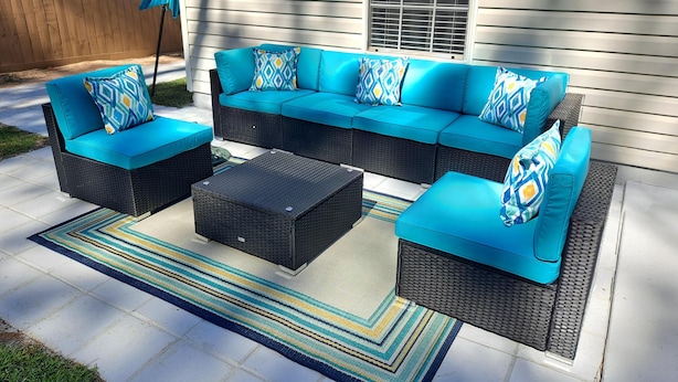 A sectional sofa with matching cushions, a coffee table, and a patterned rug on a patio. - Cozy Dream Cottage (Colorado Springs)