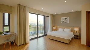 A hotel room with a large bed, a desk, a chair, and a view of the outdoors. - Villa 102 Royal Lotus cách bãi biển 5 phút (Hạ Long)