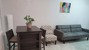 A living room with a dark brown table, two chairs, a grey sofa, and a potted plant. - Mel-Bella Retreat (George Town)