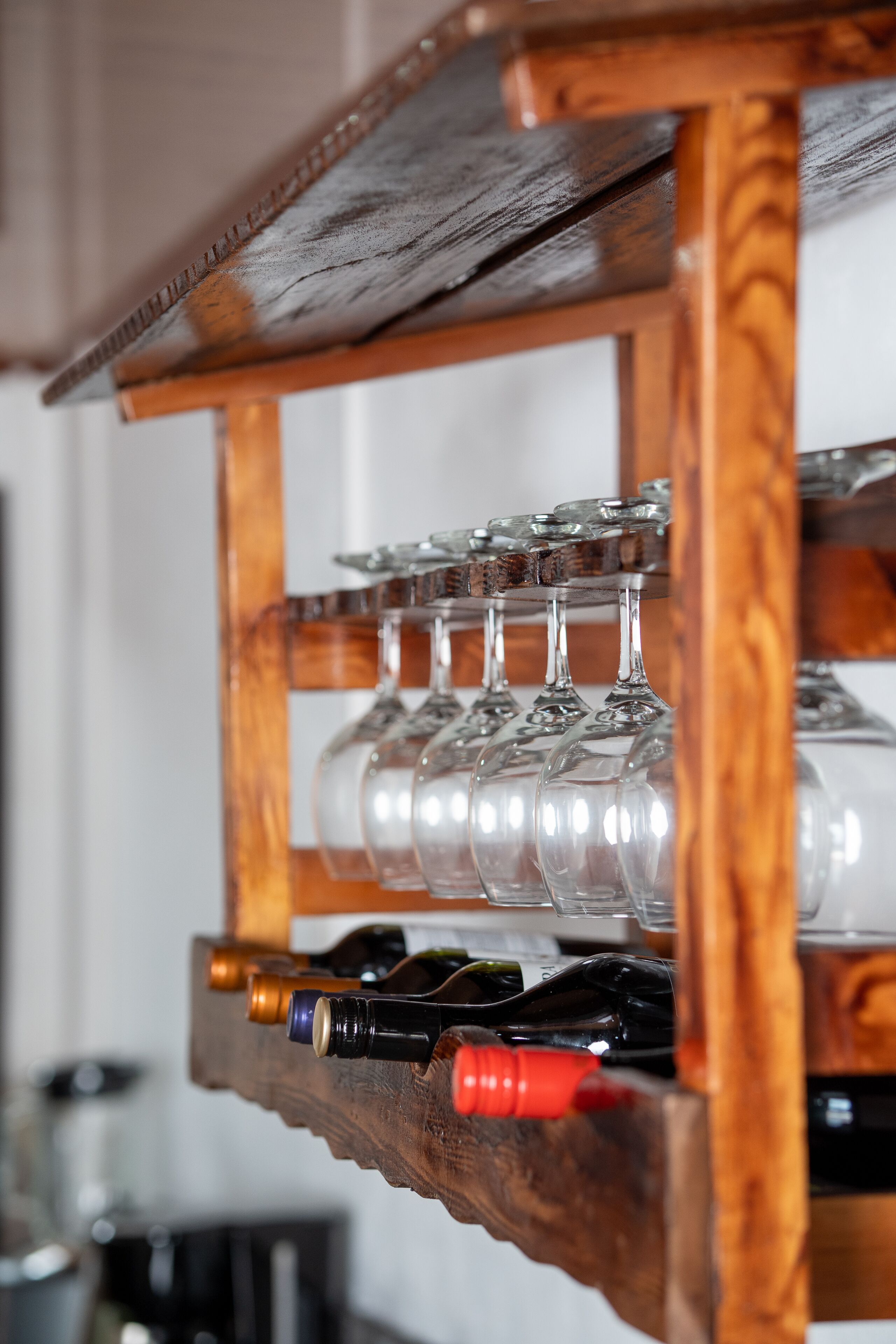 A wooden wine rack with multiple wine bottles and glasses.