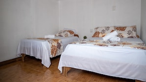Ein Zimmer mit zwei Betten, jeweils mit einem blumigen Überwurf und weißen Kissen.
