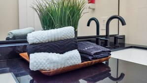 Un bagno con lavandino, specchio e una pianta in vaso.