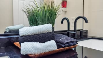 Un baño con lavamanos, espejo y una planta en maceta.