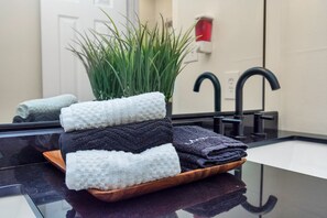 Een badkamer met een wastafel, een spiegel en een plant in een pot.