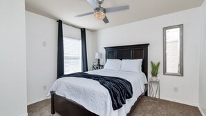 Una camera da letto con un letto, un ventilatore a soffitto, un comodino, una lampada e una finestra.