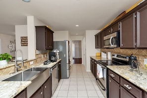A modern kitchen with dark wooden cabinets, stainless steel appliances, and a tiled backsplash.