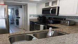 Une cuisine moderne dotée d’appareils électroménagers en acier inoxydable, de plans de travail en granit et de meubles blancs.