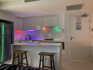 A modern kitchen with white cabinets, a marble backsplash, and a central island with stools. - Spa Bath River/Hinterland View <br>Large Size One Bedroom on Circle On Cavill  (Surfers Paradise)
