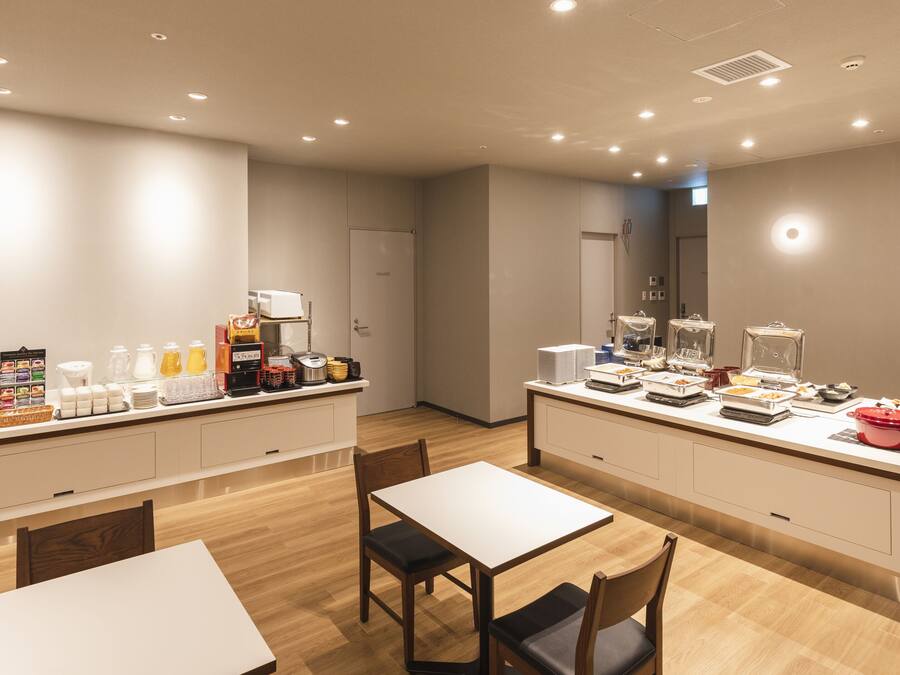 A modern hotel room with a kitchenette, a dining area, and a private bathroom.
