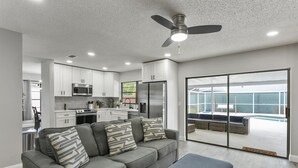 Una cocina moderna con armarios blancos, electrodomésticos de acero inoxidable y un ventilador de techo.