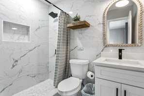 Un baño con ducha, inodoro, lavabo y espejo.