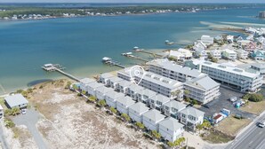 Ovenfra set udsigt over et kysthotel med flere bygninger, en mole og et strandområde.