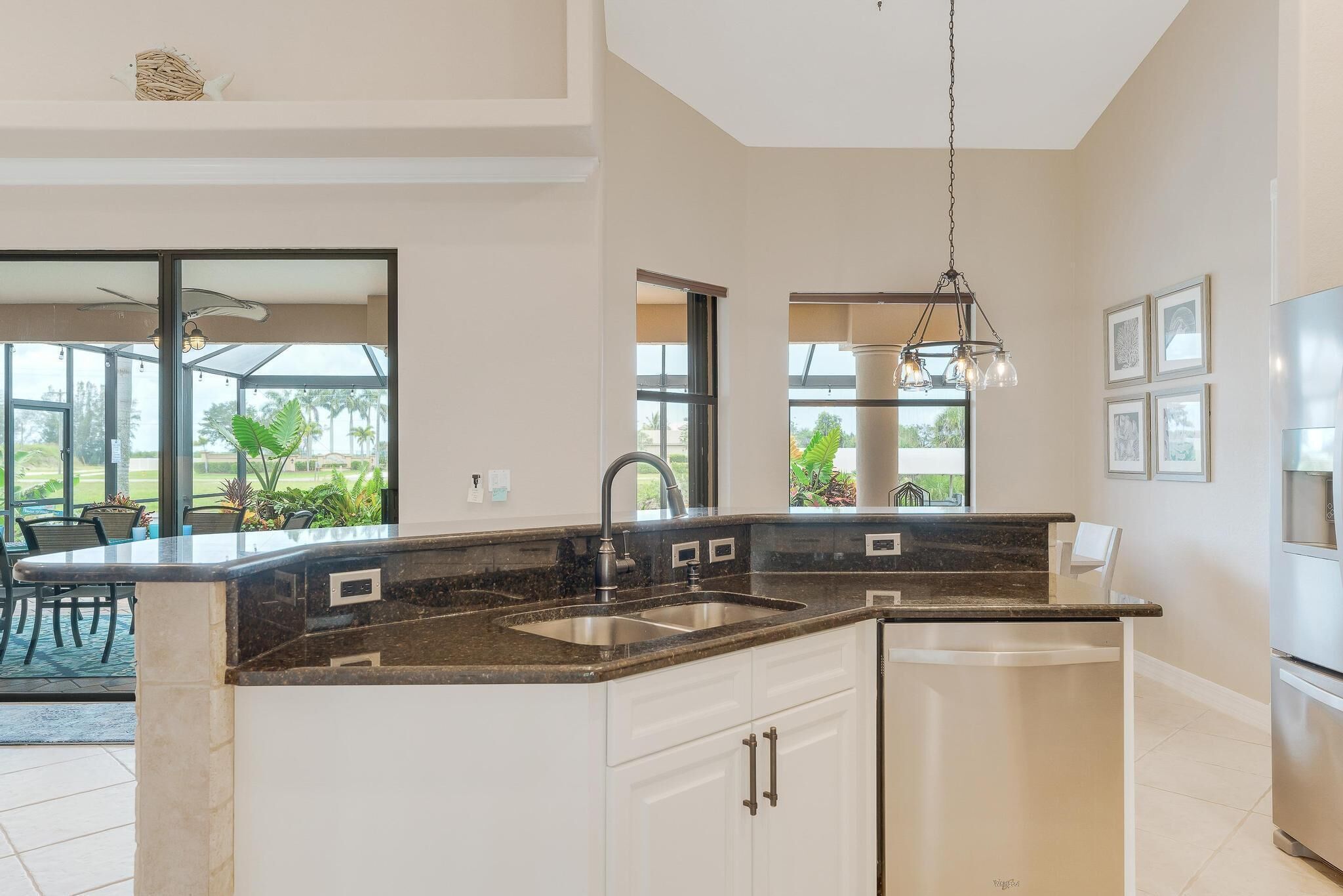 A modern kitchen with a central island, double sink, and pendant lighting.