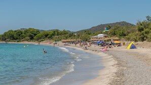 Una playa con aguas cristalinas, sombrillas y una carpa.