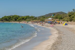 Una spiaggia con acque limpide, ombrelloni e una tenda.