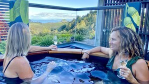 Deux personnes dans un jacuzzi, avec une vue panoramique sur un paysage.