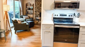 Une cuisine moderne dotée d’un four à micro-ondes et d’un four encastrés, d’une cheminée en pierre et d’un coin salon confortable avec un canapé et un lampadaire.