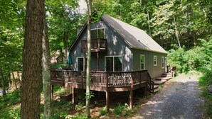 Une cabane dotée d’une terrasse, entourée d’arbres.