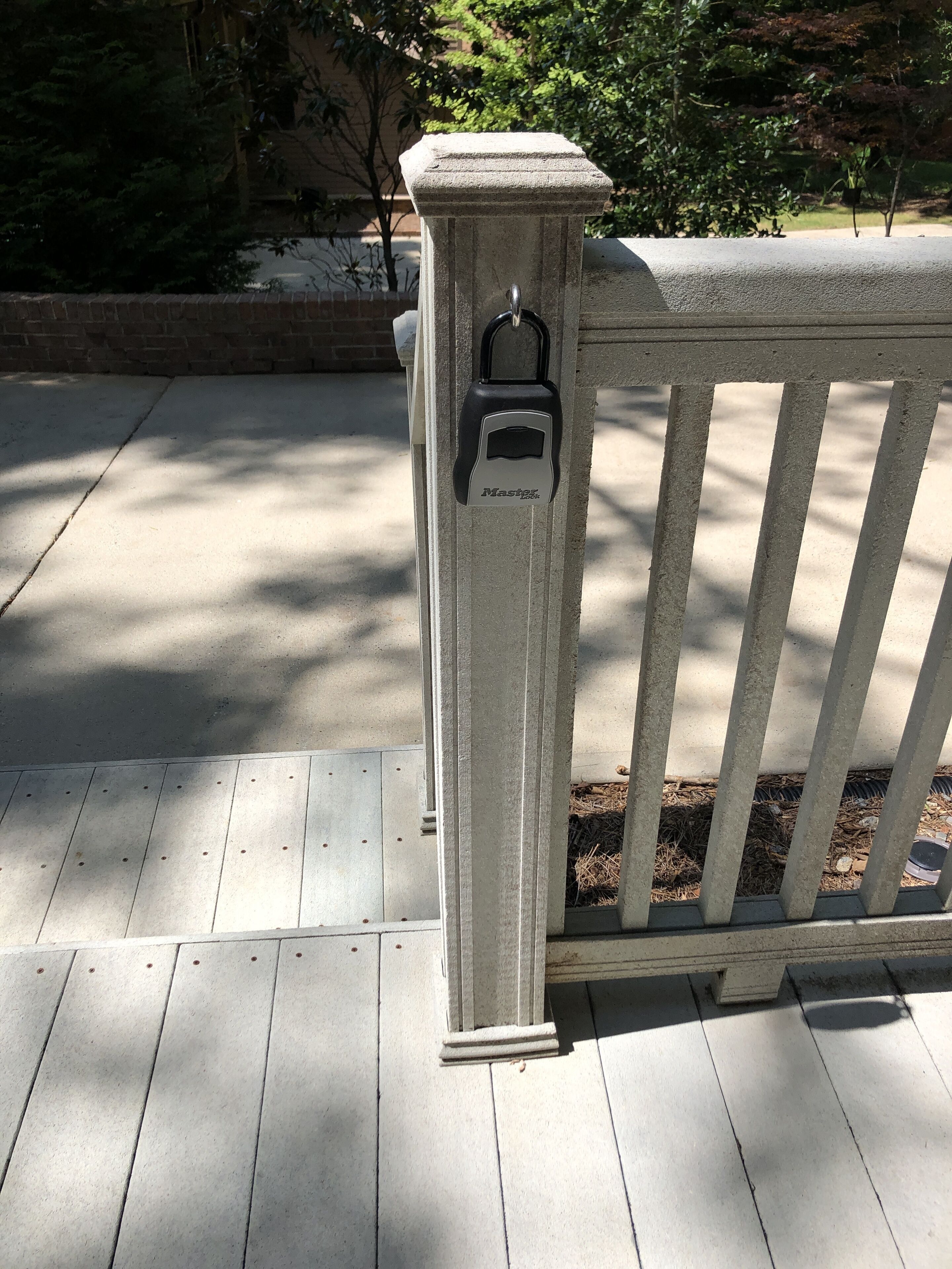 A concrete post with a padlock, part of a fence, on a wooden deck.
