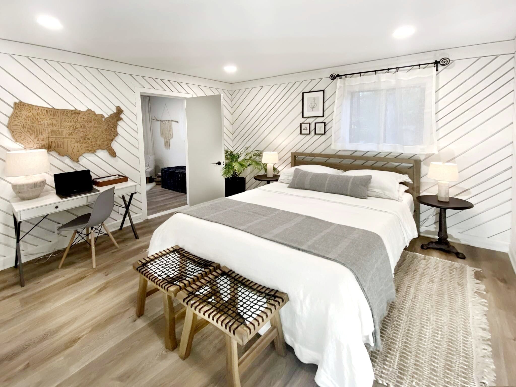 A modern bedroom with a bed, desk, and bench.