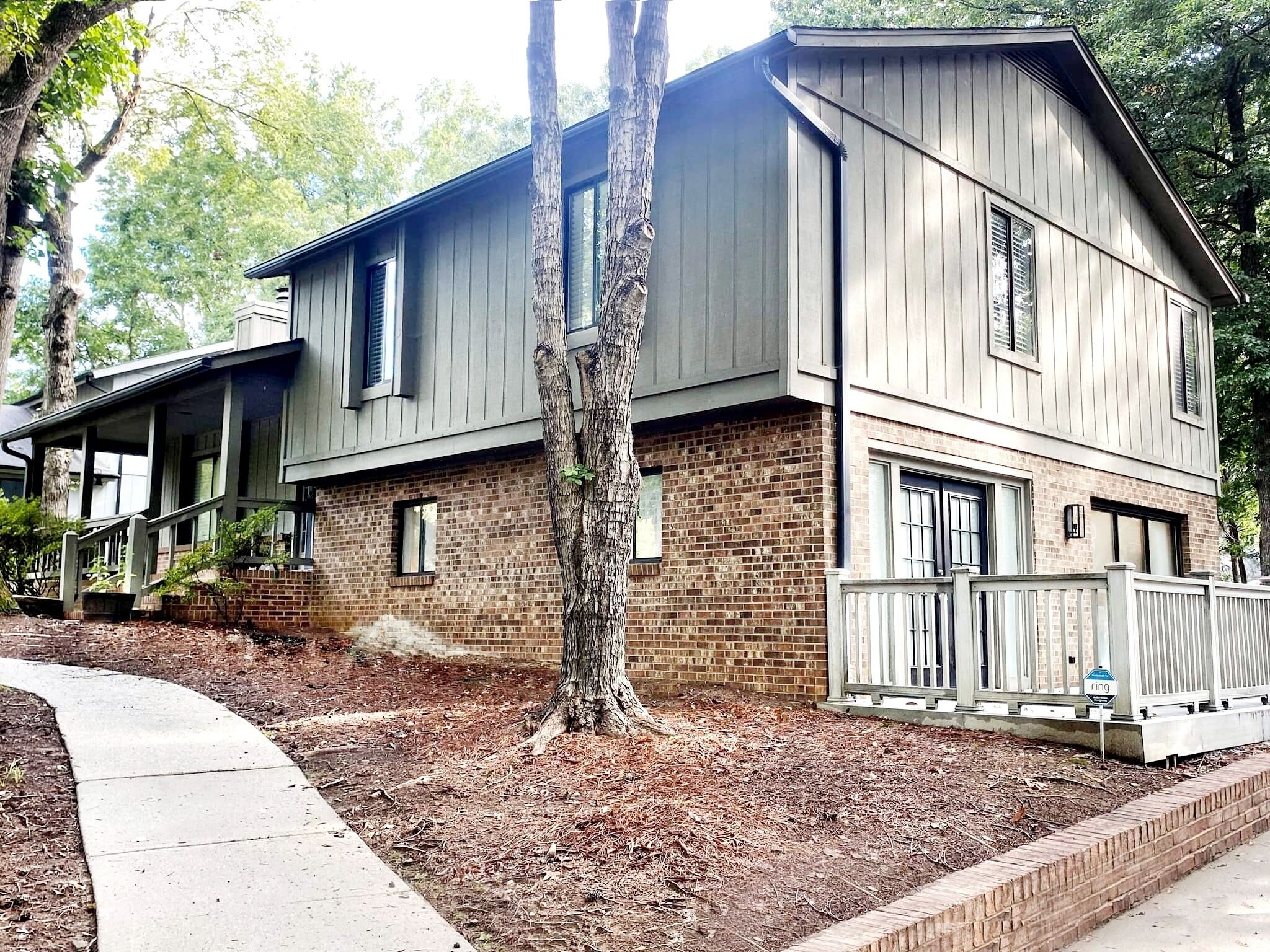 A two-story house with a brick foundation and a grey exterior.