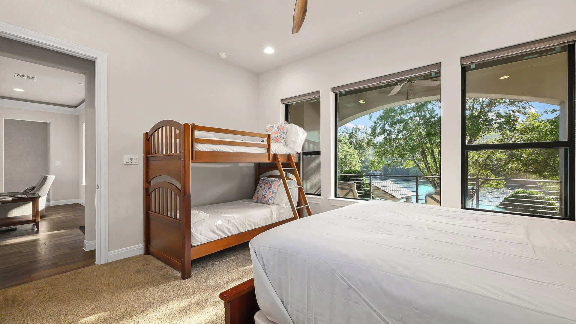 A bedroom with a bunk bed, a desk, and a view of a swimming pool.