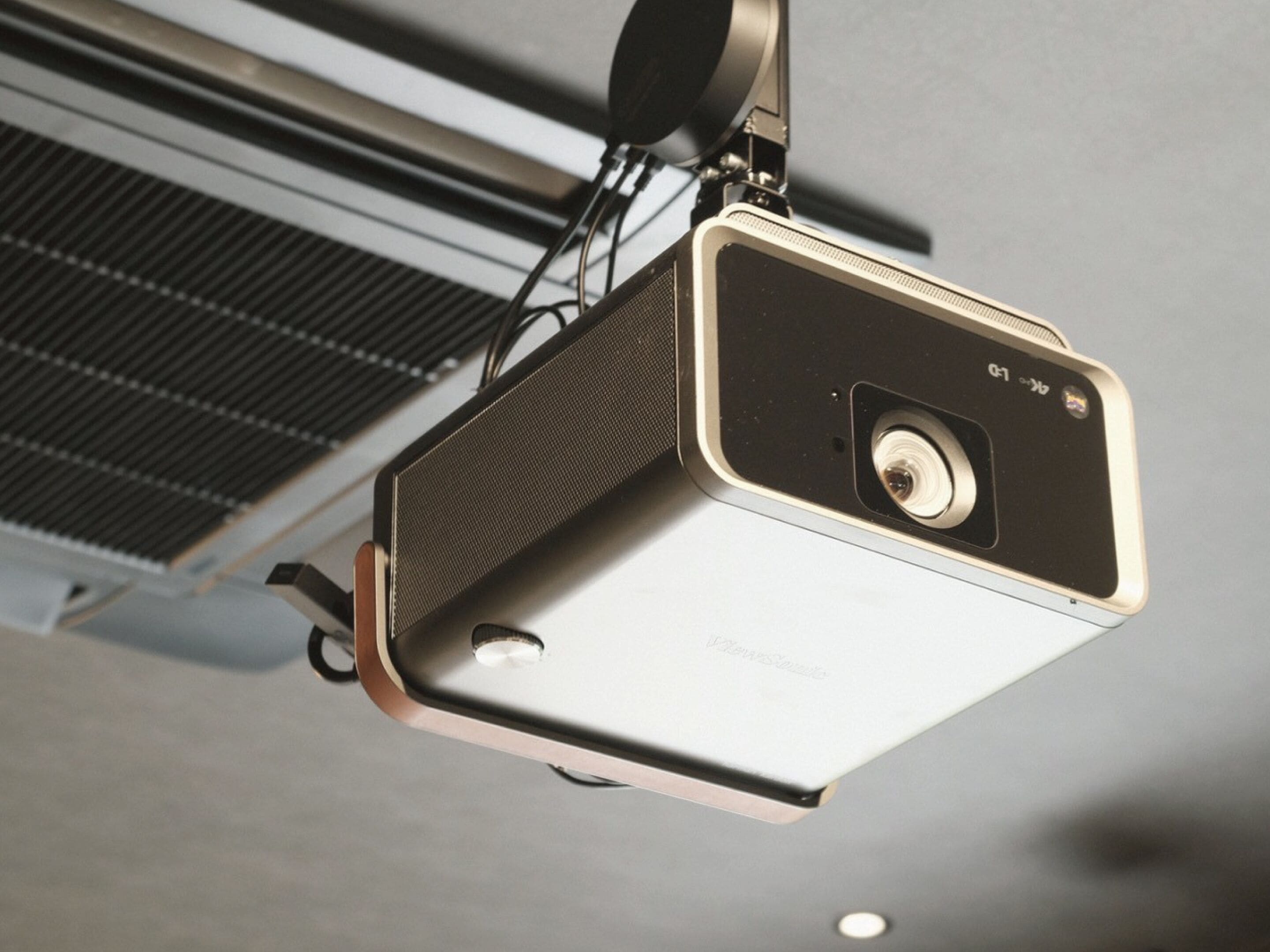 Un projecteur fixé au plafond, avec une grille de ventilation située derrière.