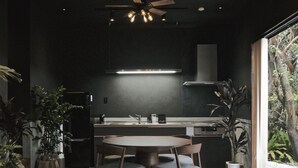 A modern kitchen with a central island, dark walls, and potted plants. - LAVA SAUNA & VILLA (Hachijo)