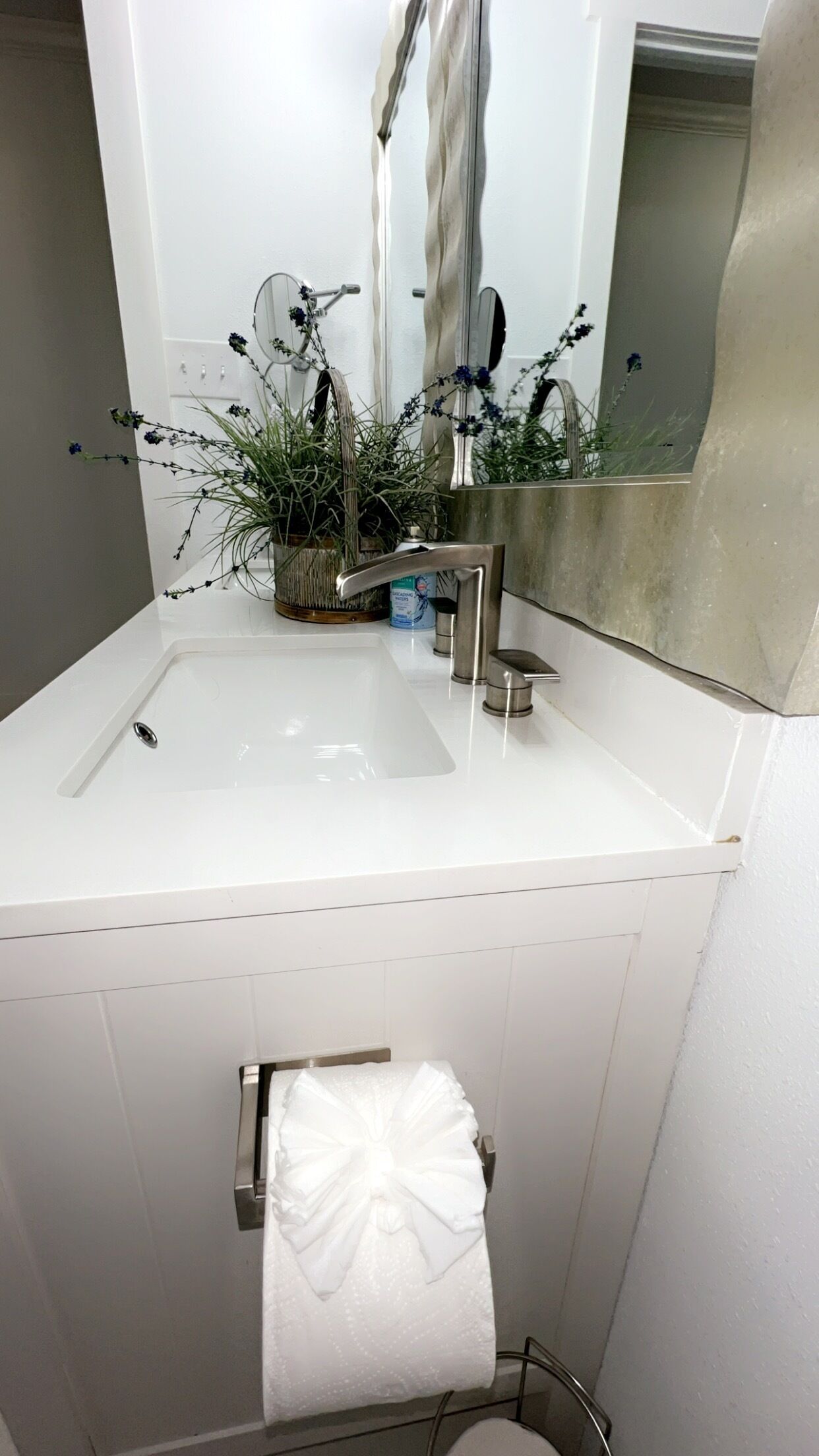 A bathroom with a white sink, a mirror, and a towel rack.