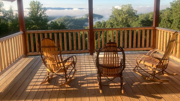 A wooden deck with two wicker chairs and a table, overlooking a forested valley. - Breathtaking Norris Lake Mountain Retreat (New Tazewell)