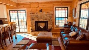 A cozy living room with a fireplace, leather furniture, and a dining area. - Breathtaking Norris Lake Mountain Retreat (New Tazewell)