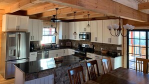 A cabin kitchen with a large island, stainless steel appliances, and a welcoming sign. - Breathtaking Norris Lake Mountain Retreat (New Tazewell)