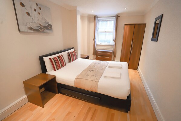 A bedroom with a bed, bedside tables, a window, and a wardrobe. - Lovely 2-Bed Apartment in London (London)