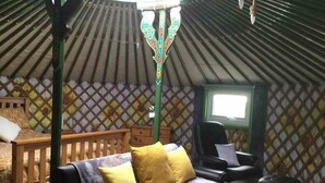 Una habitación acogedora con sofá, una silla de madera, una mesita y una ventana.