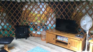 Una carpa con televisor, muebles de madera y un tapete azul.
