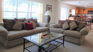 A living room with two sofas, a coffee table, and a ceiling fan.