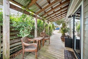 A wooden deck with a pergola, two wooden chairs, and a table.