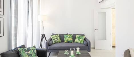 Una sala moderna con un sofá gris, un sofá negro, una mesita de centro y una lámpara de pie.