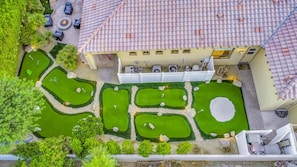 An aerial view of a courtyard with a swimming pool, surrounded by greenery and a building with a tiled roof.