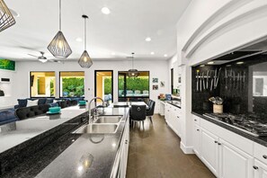 A modern kitchen with a central island, black countertops, and stainless steel appliances.
