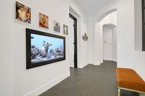 A hallway with a large aquarium display, framed photographs on the wall, and a bench.